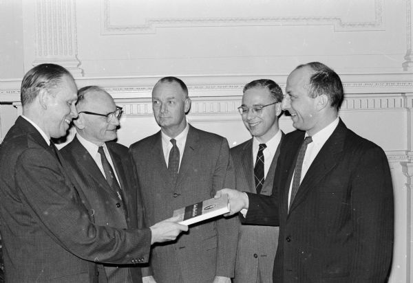 University of Wisconsin President Conrad A. Elvehjem (left) receives the first copy of a new biography of the former university president, "Charles Richard Van Hise, Scientist Progressive," from State Historical Society Director Leslie H. Fishel, Jr. (right). Other men present are, center left to right: Professors Merl Curti and Lewis Cline, and society book editor O.L. Burnette.