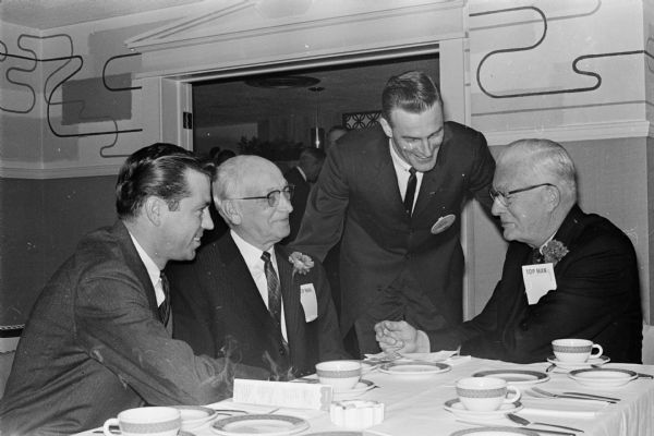 Four men who attended the annual banquet of the Madison chapter of the National Sales Executives Club gather around a table. Left to right are: William and J.J. Ryan of Pyramic Motors, and Jim and Ed Schmitz of the Hub.