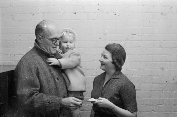 Kimball Dyer, holding his daughter Meg, hands a check from the Madison Sports Car Club to Sally Hoeveler for the <i>Wisconsin State Journal's</i> on Empty Stocking Club.