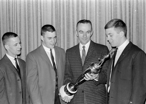 Wisconsin High School football coach Hal Metzen presents the Gene Wheeler Memorial Trophy to Pete Heebink (right) as the Badger Prep's most valuable player. At left are Glenn Lewis and Charley Buss who were elected co-captains.