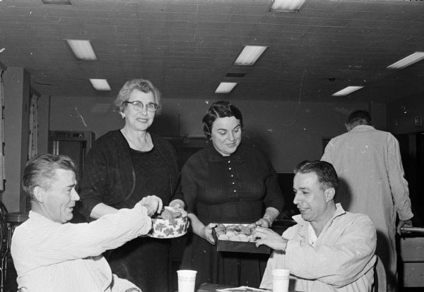 B'nai B'rith women entertain patients at the VA Hospital on Christmas Day. Martha Barth and Geraldine Netboy are shown serving cookies to patients Lyle Struemke (Watertown) on the left, and Albert Savaglio (Kenosha).  Mrs. Barth is chairman of the B'nai B'rith women's monthly parties at the hospitals, and bakes all the cookies.