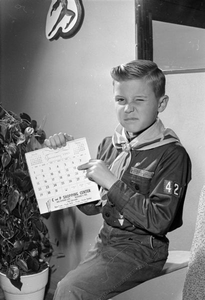 Mark Weber, dressed in a boy scout uniform, winks with one eye while pointing to number 13 on the calendar. He was born on a Friday the thirteenth and his 10th birthday will be on a Friday the 13th.