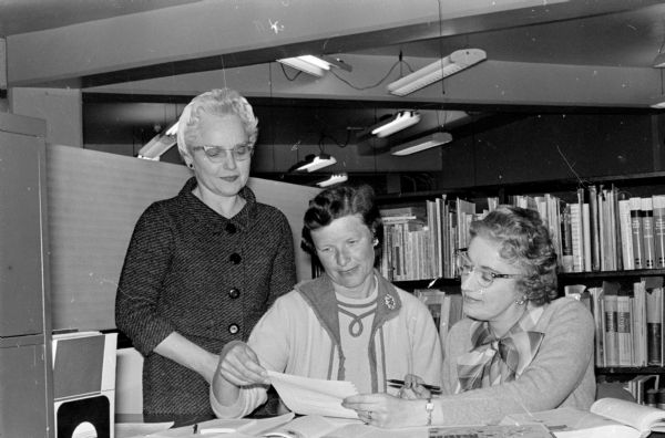 Sophie Merritt, right, history educator at the Armed Forces Institute and a half gallon blood recipient, shows Cherokee Heights Red Cross Bloodmobile Chairman Pauline Wixson, center, and Hazel Hofsteen, standing, co-chairman, her own teaching invention, a textbook page which can be filled out by a correspondence student GI, ripped out and mailed to his school for high school or college course credit. Merritt was also a World War Two Wave.