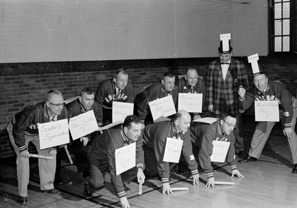 Team Captains for the YMCA membership drive pose as runners at the starting line. First row, left to right, are: George Field, Russ Weitz, Dick Callaway, and Red Wilson. Second row, left to right, are: Al Sabo, Orin Thompto, Harland Klipstein, Jim Lewis, Russ Bauman, and Arlie Mucks.