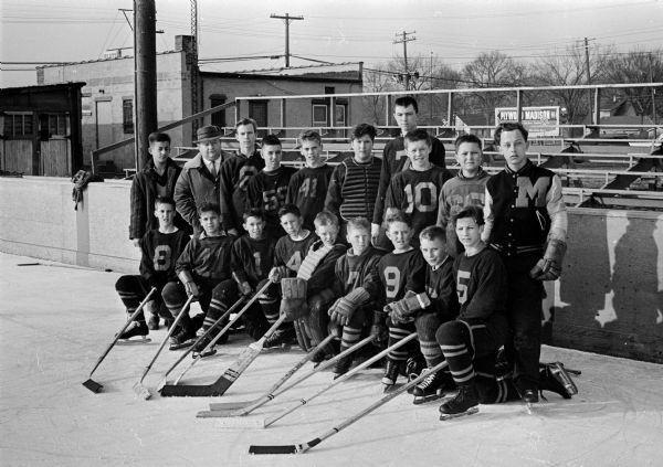 Outdoor group portrait of the South Siders hockey team who will be playing for the championship of the Wisconsin State Bantam League Tournament. The members are shown in uniform, holding their hockey sticks.