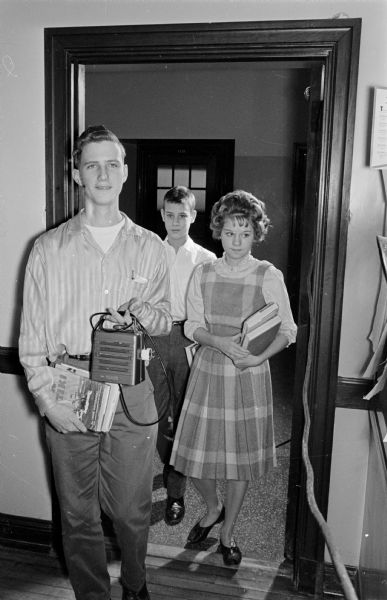 Kenneth Ackerman is carrying a two-way speaker into English class at East High School where it will be used to connect a homebound student (Jerry Novick) to his class. Two other unidentified students are following Kenneth.