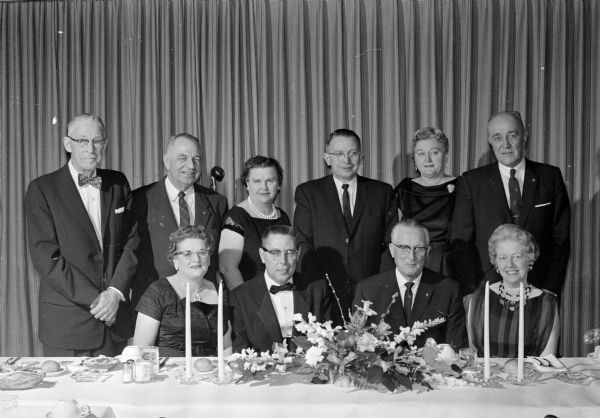 Madison and state Elks Club dignitaries gather at the head table for the initiation banquet of Madison lodge #410, held in the Elks clubhouse at 120 Monona Drive. Standing left to right:  Arthur Devine, Chester Weed, Mrs. Weed, Kenneth Sullivan, Virginia Sullivan,and Frank Lynde. Seated left to right: Jane Webster, Thomas Webster, Dr. M.J. Junion, and Mrs. Lynde.