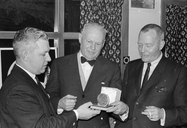 Arthur Towell (center), president of the Arthur Towell advertising agency, receives the Silver Medal Advertising Award at a meeting of the Madison Advertising Club preceding National Advertising Week. At the left is Hugh Brady, a Madison advertising executive, and at the right is guest speaker Owen Smith of Chicago who spoke at the meeting.