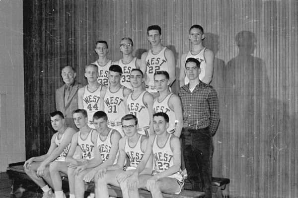 The Madison West High School basketball team won its division in the Big Eight Conference race with a 12-2 record. Coach Clark Byam's squad includes, left to right:  First row: Ron Schenk, Brian Smith, Pete Smith, Jim Drake, Jim Doyle. Second row: Coach Byam, Phil Scholl, Guy Solie, Tim Smith, John Peterson, manager Dan Aspinwall. Third row: Bob Niebuhr, Rene Burkhalter, Ron Risely, John Norsetter.