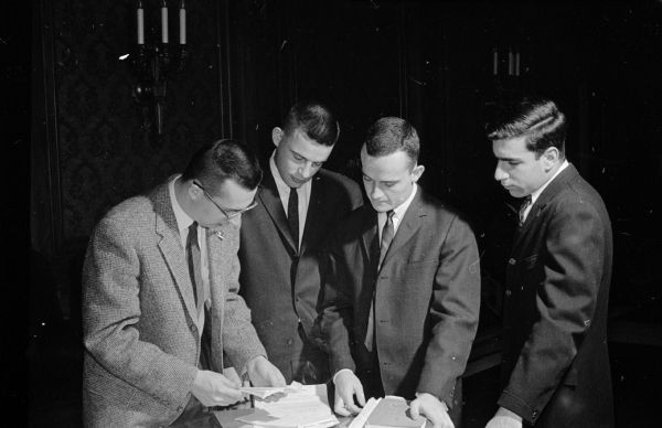 Members of opposing parties meet before a session of the "United States Senate" during the annual mock senate event in the Wisconsin Assembly chamber sponsored by several University of Wisconsin student groups. Left to right are Dave Obey, Dave Rice, Jim Nafziger, and Dick Martin.