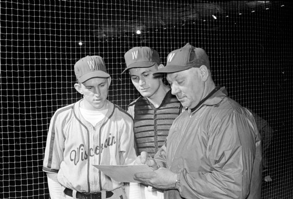 University of Wisconsin baseball coach, Dynie Mansfield, and players discuss strategy before departing for games in Tempe, AZ. Shown, left to right, are: pitcher Ron Krohn, catcher Tom Handford, and Coach Mansfield.