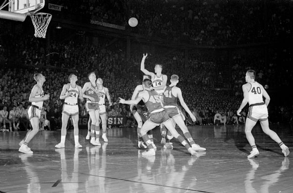 Action shot from the Waukesha versus Rice Lake game in the 1961 State High School Basketball Tournament. On Thursday Madison East beat Eau Claire, Milwaukee Lincoln beat Manitowoc, Rice Lake beat Reedsburg and Waukesha beat Shawano.  On Friday Milwaukee Lincoln beat Madison East, Rice Lake beat Waukesha and in the consolation games Manitowoc beat Eau Claire and Shawano beat Reedsburg. On Saturday Milwaukee Lincoln beat Rice Lake for the title.