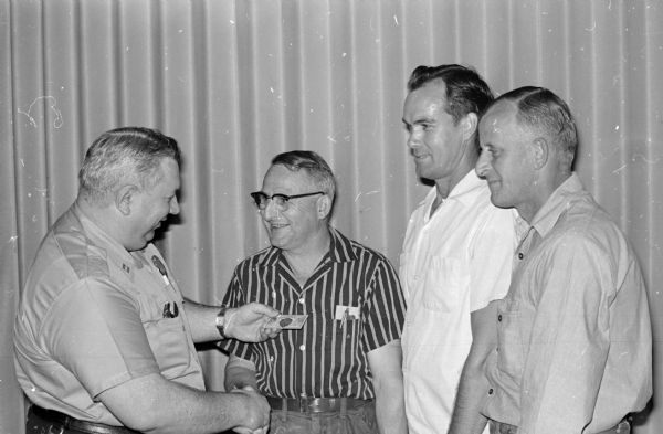 Three Madison Railway Express agency drivers receive awards for safe driving from Capt. W.A. Randall, left, of the Madison police department. The drivers and the years they drove without accidents are, left to right:  Francis Penn, nineteen; Glenn Alderson, eight; and Richard Oakey; thirteen.