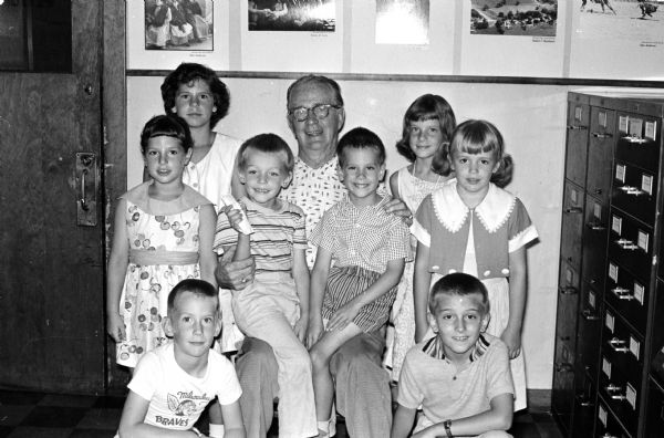 A group of children who put on a comedy show to benefit handicapped and underprivileged boys and girls through Roundy's Fun Fund, are shown surrounding Roundy Coughlin. Front row left to right:  Jimmy Fandrich and John Vanderbloemen. Second row left to right:  Cheryl Sweet, Billy Vanderbloemen, Russell Conlon, and Serena Vanderbloemen.  Back row left to right:  Vicki Sweet, Roundy Coughlin, and Anne Bernauer.