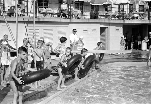 The Aquacade at the Maple Bluff Country Club pool includes races, family dinner and an evening show. Ready for the tube race are, left to right, Mark Herro, Sarah Beck, Mary Beach, and Kate Keeley.