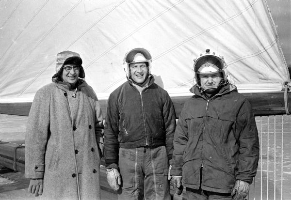 Three men dressed in winter clothing stand in front of an iceboat.  Two additional images show four other men standing in front of iceboats.