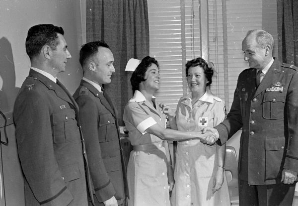 Truax Field's Red Cross recognition tea featured a ten-year service pin given to Margaret Hoffman. Shown left to right:  Col. Olin E. Gilbert, Truax Field commander; Capt. Richard N. Betz, director of the base medical corps; Mrs. Hoffman; Lois Tainsh, Red Cross Truax unit chairman; and Brig. Gen. Kenneth H. Gibson, commander of the Chicago Air Defense Sector.