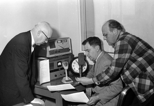 City Civil Defense Director Richard Wilson (left) and two Madison radio announcers take part in a nationwide CONELRAD test as part of the eighth annual "Operation Alert" test of civil defense facilities in the U.S. Joining Wilson in the broadcast are WHA's Roy Vogelman (center) and WIBA's Al Gilbert.