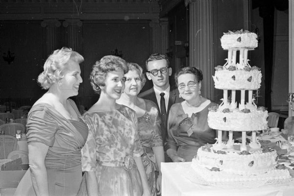 Admiring a four-tiered anniversary cake at a banquet celebrating the 40th anniversary of the Sigma Alpha Iota music sorority are, left to right, Helen Peters; JoAnne Brown, Shell Lake; Viginia Quisling; Thomas Buckhauser, Chicago; and Eleanor Nerdrum, general chairman of the event.