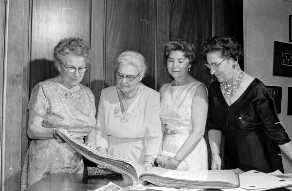 Four women look at a scrapbook prior to a banquet celebrating the 40th anniversary of the Sigma Alpha Iota music sorority. They are left to right: Josephine Iltis, the first member of the sorority; Irene Eastman, charter member; Winifred Brown, charter member; and Mrs. Stevens Dewire, Delmar, New York, charter member and first secretary of the chapter.