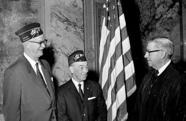 Peter Altenhofen (left), Milwaukee, of the Red Arrow Association, and Ruben Cain, Milwaukee, of the Cudworth Post #23 of the American Legion of MIlwaukee present a new American flag to Chief Justice John Martin (right) in honor of May 1 Law Day.