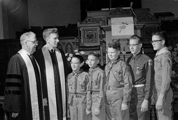 Four Boy Scouts and an Eagle Scout, all members of the First Methodist Church, are  presented with God and Country awards. Reverend Dr. Carl Stromberg (left), pastor of the church, and the Reverend Thomas Jarrell, assistant pastor, present the awards. The boys are, left to right: Jack Zimbech, Randy Wade, Jack Heady, Jeff Haines (the Eagle Scout), and Roger Marsh.