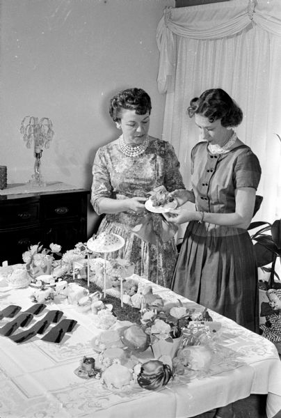 Two wives of Zor Shriners prepare decorations for the Zor Shrine ceremonial banquet at the Hotel Loraine. Dorothy Moore and Jean Wheeler inspect some miniature hat trees.
