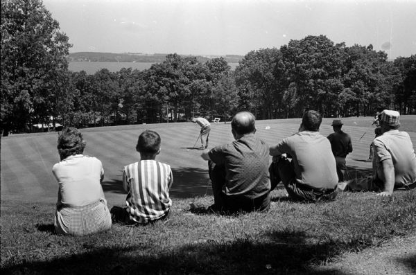 Jack Allen lines up a four-foot putt on the 18th green at Blackhawk Country Club in the Madison City Men's Golf Tournament. Spectators are sitting in the foreground.