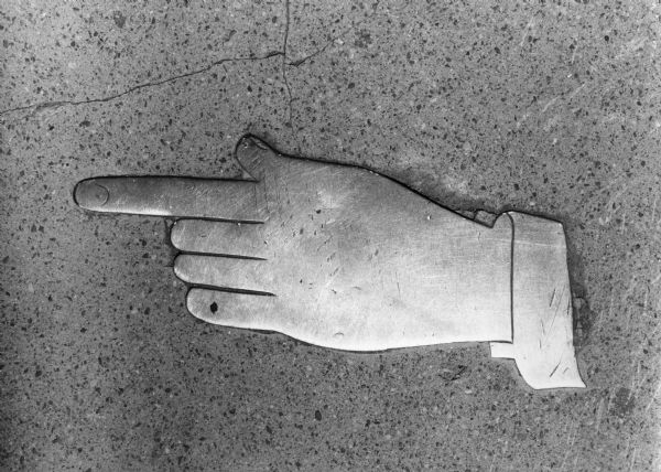 Detail of hand with pointing index finger in the sidewalk in front of the old Madison Gas and Electric Company building (aka Darwin Clark Building), at 120 - 126 East Main Street.