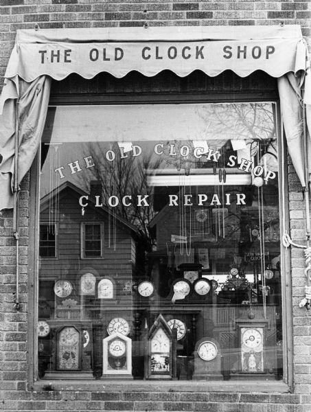 Exterior view of The Old Clock Shop owned by P. Tock at 1343 Williamson Street with clocks displayed in the window.