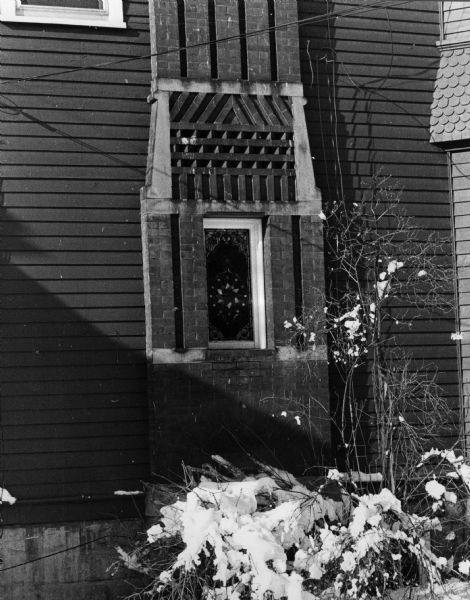 Exterior view of the Skelton House at 313 West Wilson Street showing a stained glass window in the red brick chimney.