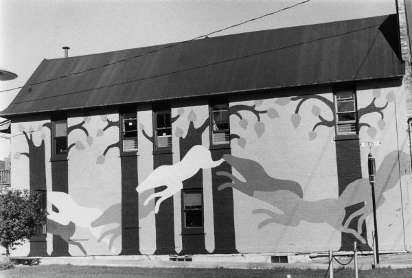 Exterior view of a wall of University of Wisconsin Madison office building that was decoratively painted by students with a tree design.