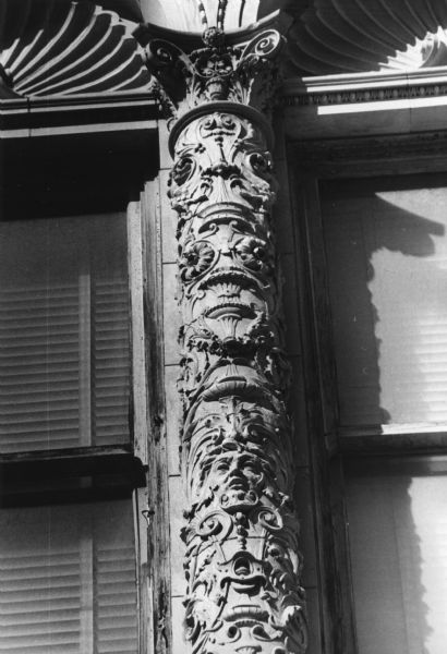 Decorated pillar on the facade of the Baskin, Olson, and Veerhusen Company at 7 North Pinckney Street. One detail of the ornamentation is a carved face.