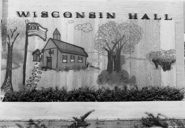 A folk art painting of a schoolhouse and an American flag, which was painted on boards temporarily covering a broken window at Wisconsin Hall at 126 Langdon Street. At the time, Wisconsin Hall housed the offices of the Wisconsin Department of Public Instruction.