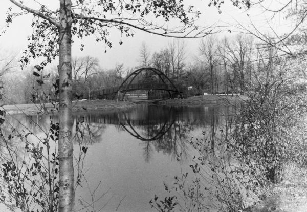 View of the Tenney Park bridge casting a reflection in the water of the lagoon.
