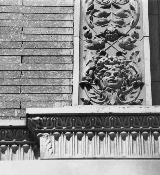 Exterior decorative detail featuring carved columns decorated with faces, vines and leaves on Baskin O & V at 7 North Pinckney Street.