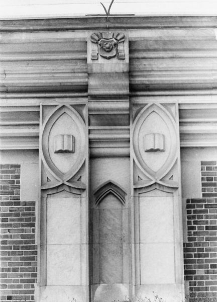 Two carved stone books on the exterior of East High School reflecting a decorative Gothic architectural style.