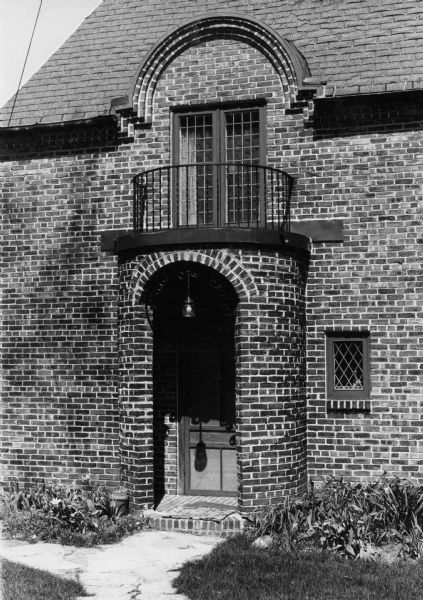 Brick entrance of a house at 150 North Prospect Street. Its small, leaded windows, ironwork, and arch reflect the 19th Century Regency style.