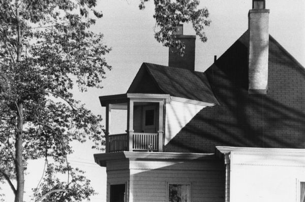 A balcony on a house at 1228 Sherman Avenue, formed with the railing at the roof edge in front of the dormer.