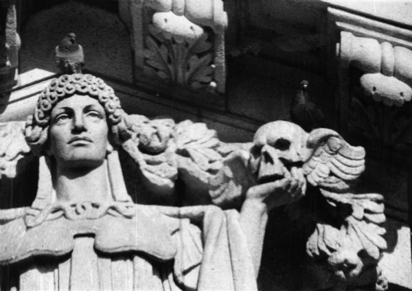 Sculpture representing Wisdom above the south portico of the Wisconsin State Capitol building along South Hamilton Street. Wisdom holds a winged skull which represents thought.