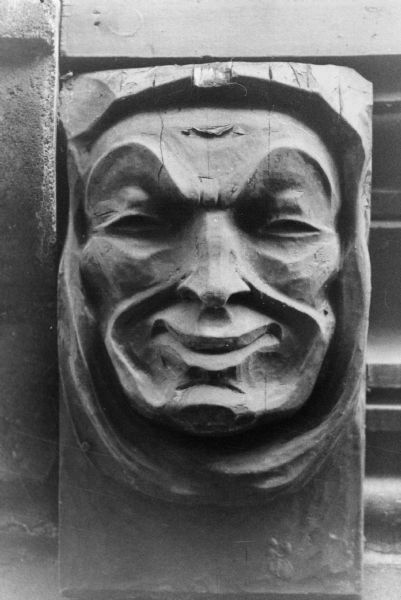 A carved smiling face detail on the end of a wooden beam on Le Chateau residential cooperative at 636 Langdon Street. It's one of four decorative faces, the others displaying tears, laughter and ill-temper.