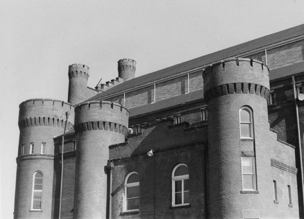 Exterior view of the five turrets on the Armory (Red Gym or Old Red), on the University of Wisconsin-Madison campus. The turrets are topped with crenels, which are slots that allow weapons to be fired while the defender remains protected.