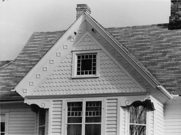 A wooden gable on a house at 1724 Jefferson Street ornamented with octagonal shingles, intricately carved brackets, and decorative, carved squares.