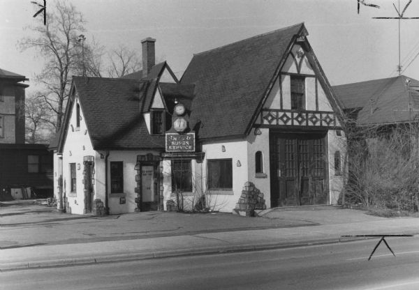 Building at the corner of Regent and Mills Streets with a unique, storybook-style design. The building was used as a gas station and then a boat repair shop.