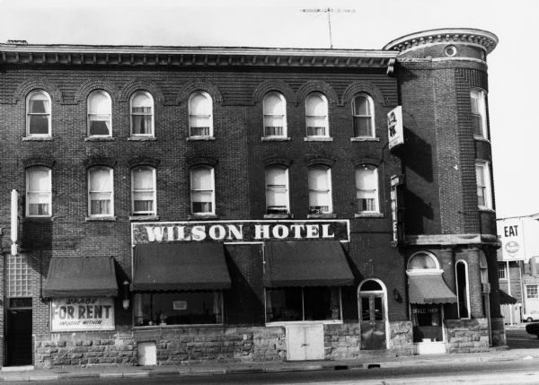 Exterior view of the Wilson Hotel on East Wilson Street. Architectural details include a turret, arched windows and textured brickwork.