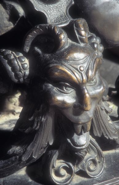 Detail of one of two bronze andirons, this one a satyr, in the Governor's Conference Room at the Wisconsin State Capitol. The andirons depict cherubs and fruit around an ornamental base with urns, satyrs and mermaids.