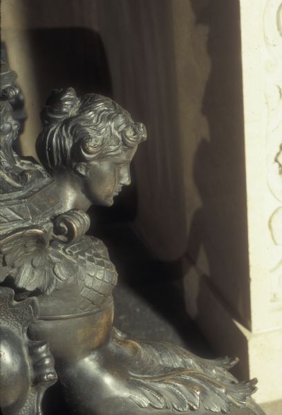 Detail of one of two bronze andirons, this one a mermaid, in the Governor's Conference Room at the Wisconsin State Capitol. The andirons depict cherubs and fruit around an ornamental base with urns, satyrs and mermaids.