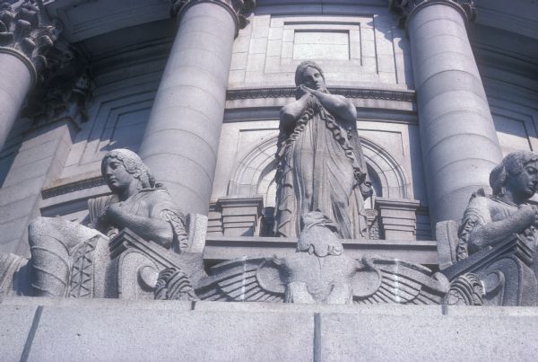 One of four allegorical statuary groups, by sculptor Karl Bitter, on the exterior of the Wisconsin State Capitol. This one is named "Faith," and is above the fourth floor facing Martin Luther King Jr. Boulevard. Each of the four statuary groups around the dome consist of three figures.