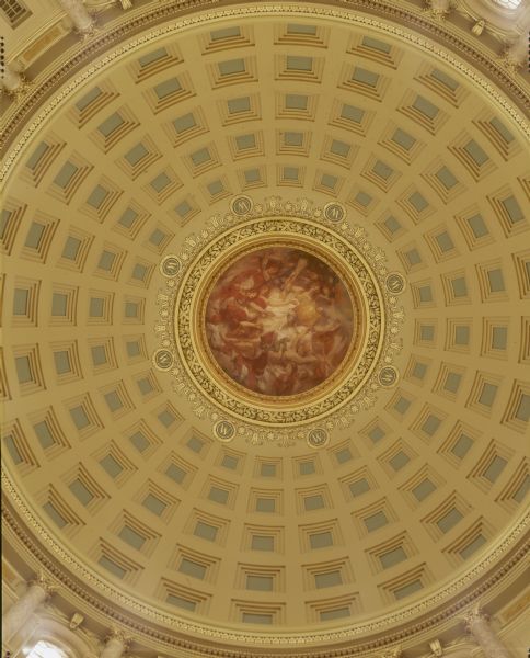 "Resources of Wisconsin," a painting by Edwin Howland Blashfield. The painting is in the inner dome of the Wisconsin State Capitol, and is painted in a segment of a sphere that is 34 feet in diameter and approximately 13 feet high. It sits above a gold entablature and is lit from below. A woman representing Wisconsin is enthroned on clouds and is holding the escutcheon of the Wisconsin State Coat of Arms. Below her are other women wrapped in the United States flag and holding products of the state, including grapes, lead, copper, tobacco, and fruit.