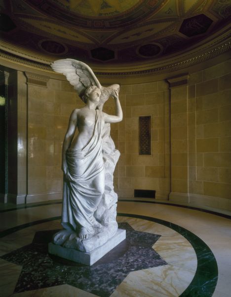 "Genius of Wisconsin" statue, originally sculpted by Helen Mears for the Columbian Exposition of 1893. It was later recreated in marble by the Piccirilli Brothers and funded by women of Wisconsin. It now stands at the first floor southeast entrance of the Wisconsin State Capitol.